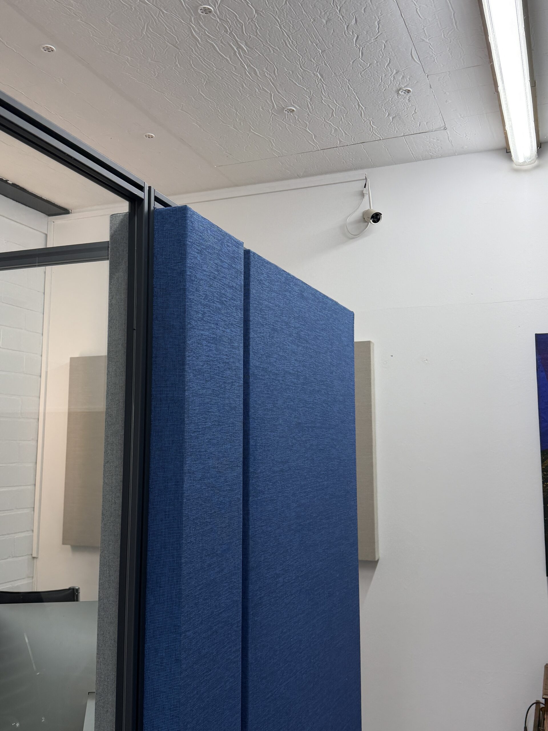 Blaues Akustik-Stellwand-System als modularer Raumteiler in einem modernen Büro zur Reduzierung von Umgebungslärm.